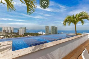 A rooftop pool with a view of high-rise buildings and the sea.