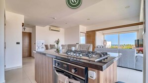 Een moderne keuken met een centraal eiland, een ingebouwde oven en uitzicht op de woonkamer.