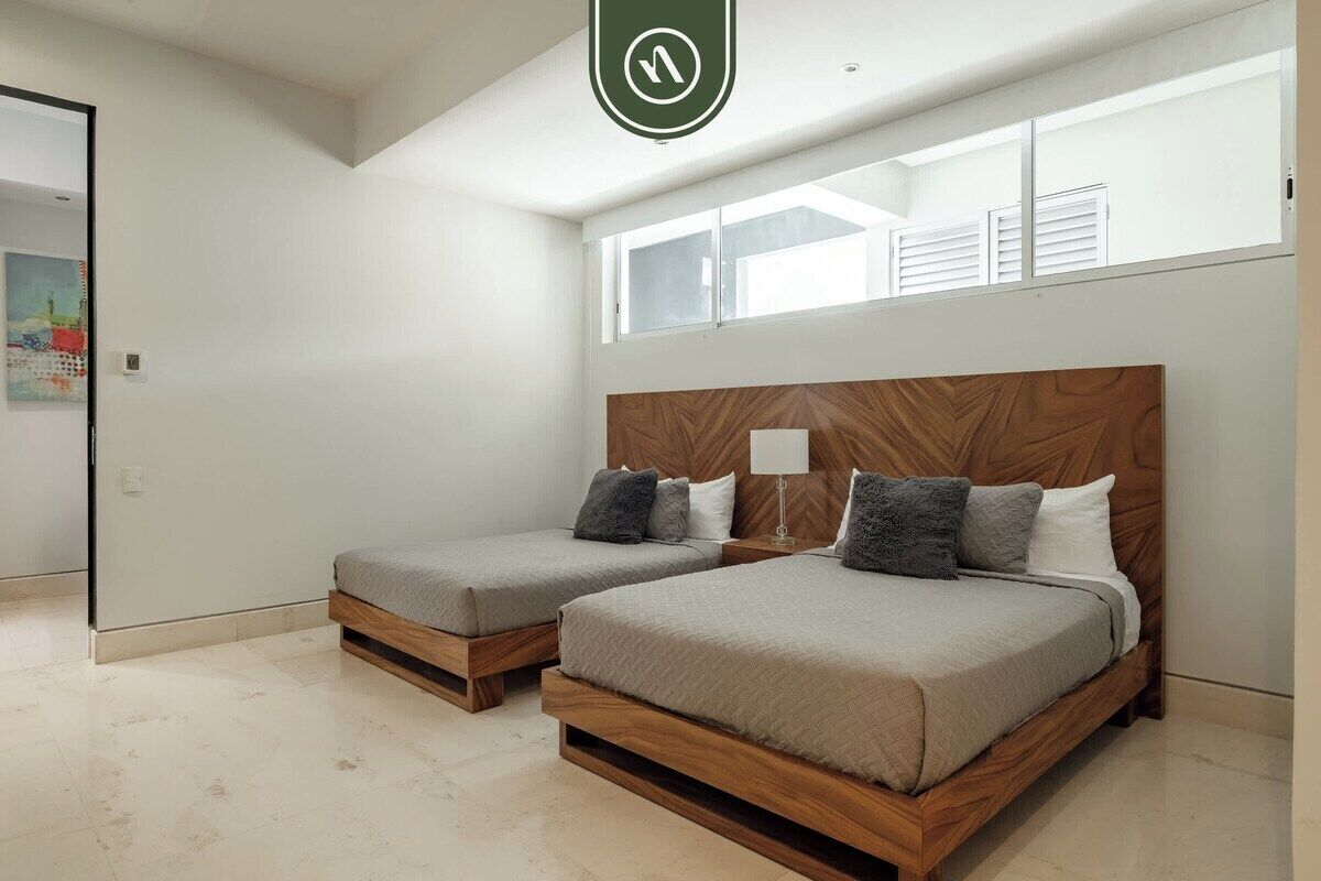 A bedroom with two beds, a window, and a door.