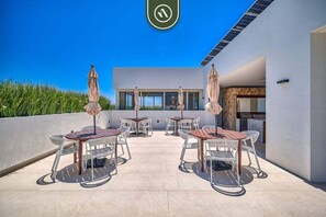 A rooftop patio with outdoor furniture, a view of the sky, and a building in the background.