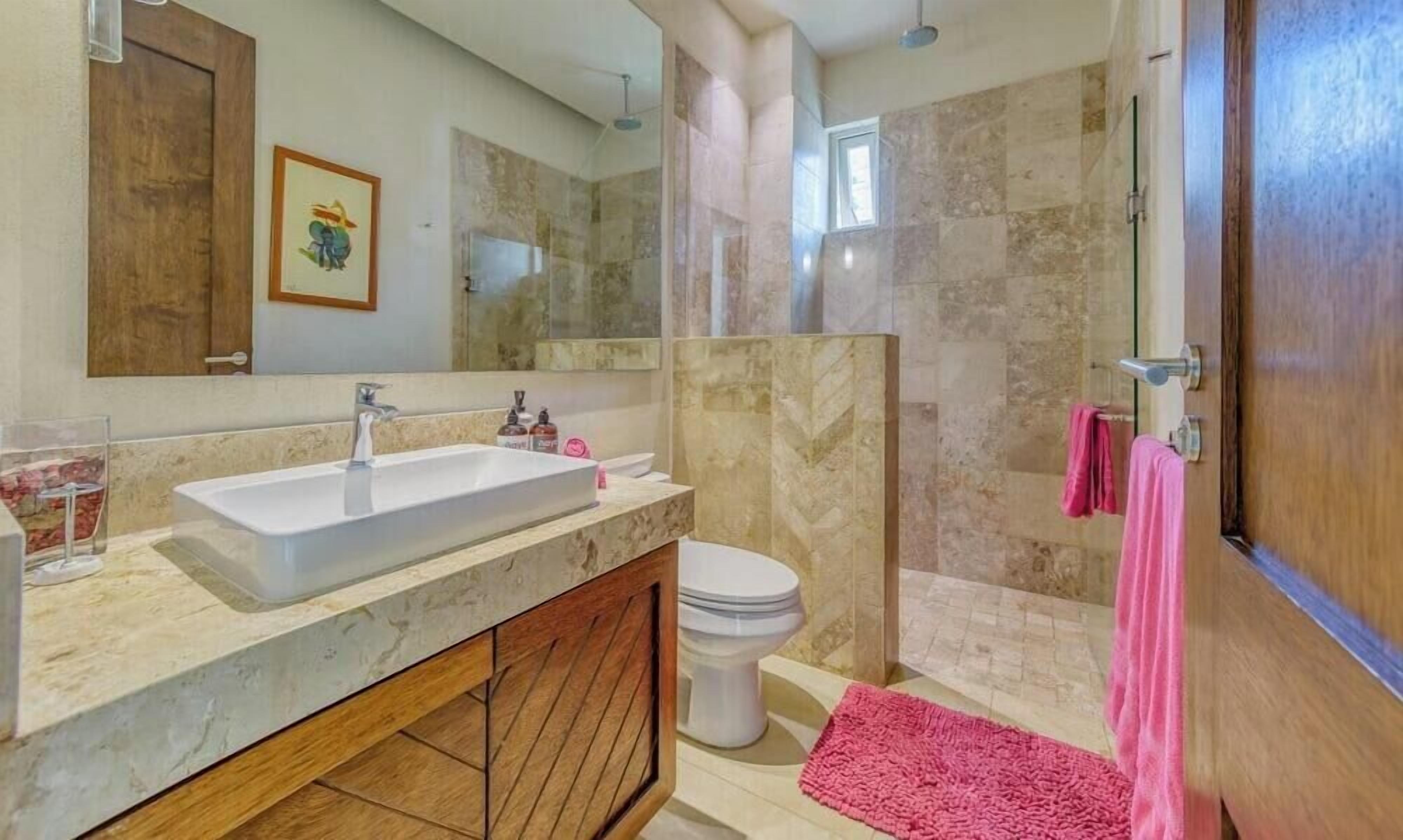 Une salle de bain avec un grand miroir, un lavabo, des toilettes et un espace douche.