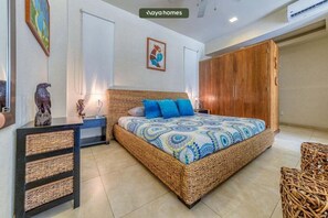 Quarto com cama de vime, guarda-roupa e mesa de cabeceira.