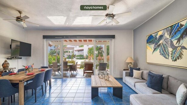 A spacious living area with a dining table, sofas, and a ceiling fan.