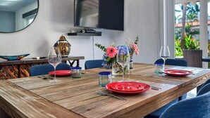 A dining table set with red plates, wine glasses, and a vase with flowers.