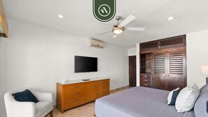 A bedroom with a bed, a TV, a wardrobe, and a ceiling fan. - Stunning 2 BR Condo - Oceanview Terrace - Downtown (Puerto Vallarta)