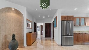 A modern kitchen with a stainless steel refrigerator, wooden cabinets, and a tiled backsplash. - Stunning 2 BR Condo - Oceanview Terrace - Downtown (Puerto Vallarta)