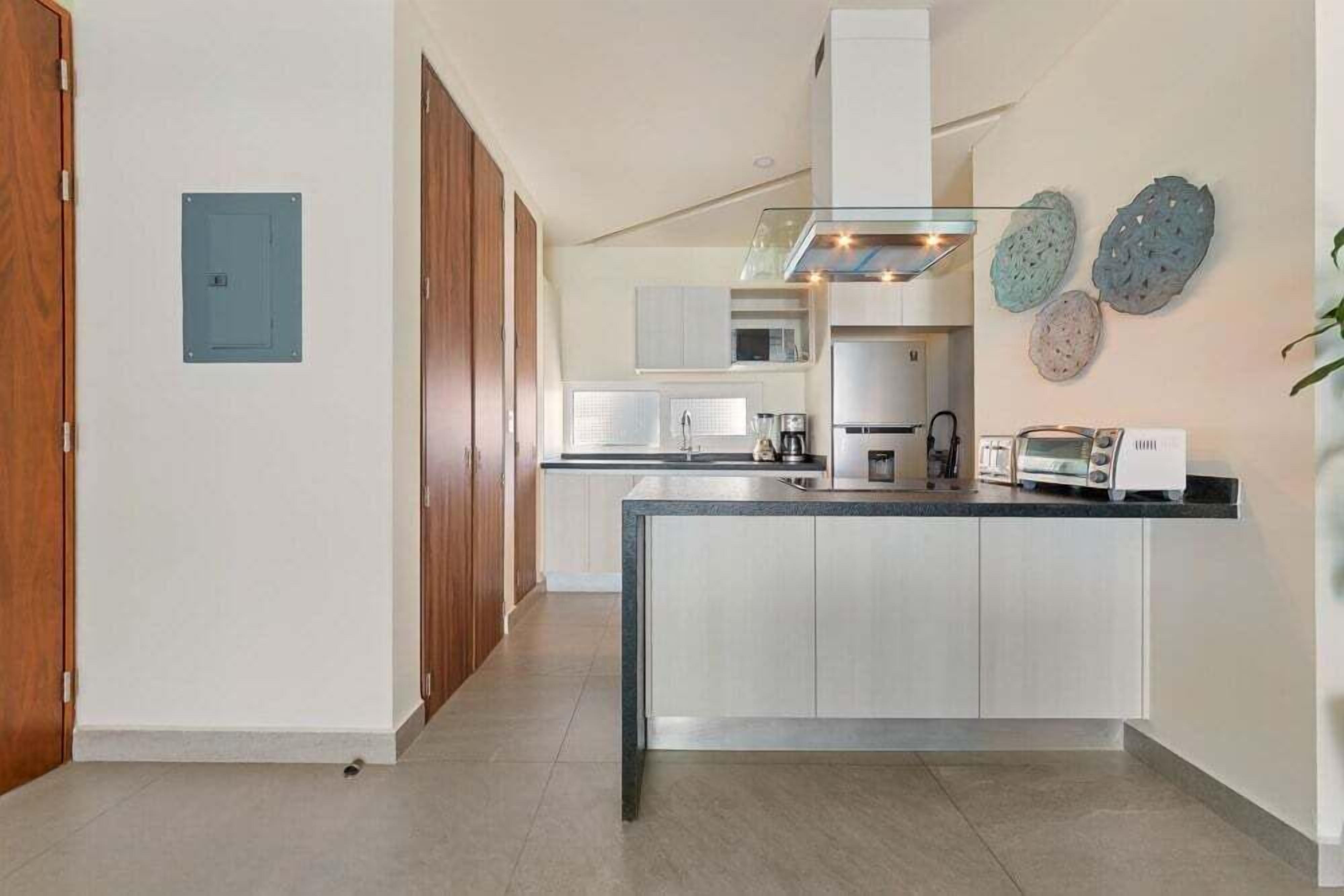 A modern kitchen with a central island, white cabinetry, and a microwave.