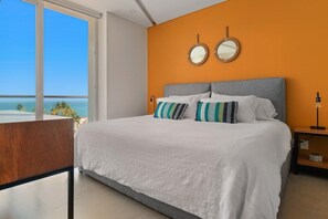 Quarto com uma cama grande, dois espelhos redondos e vista para o mar.