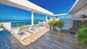 Una terraza en la azotea con piscina, sillas de descanso y plantas en macetas.