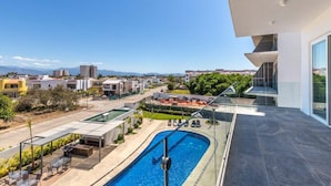 A modern residential building with a rooftop pool, outdoor seating, and a view of a residential area. - Believe Condo Flamingos Believe 302 (Bucerías)