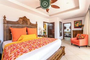 A hotel room with a large bed, a wooden headboard, a ceiling fan, and a red armchair. - Amazing House With Private Terrace - Private Pool (Cabo San Lucas)