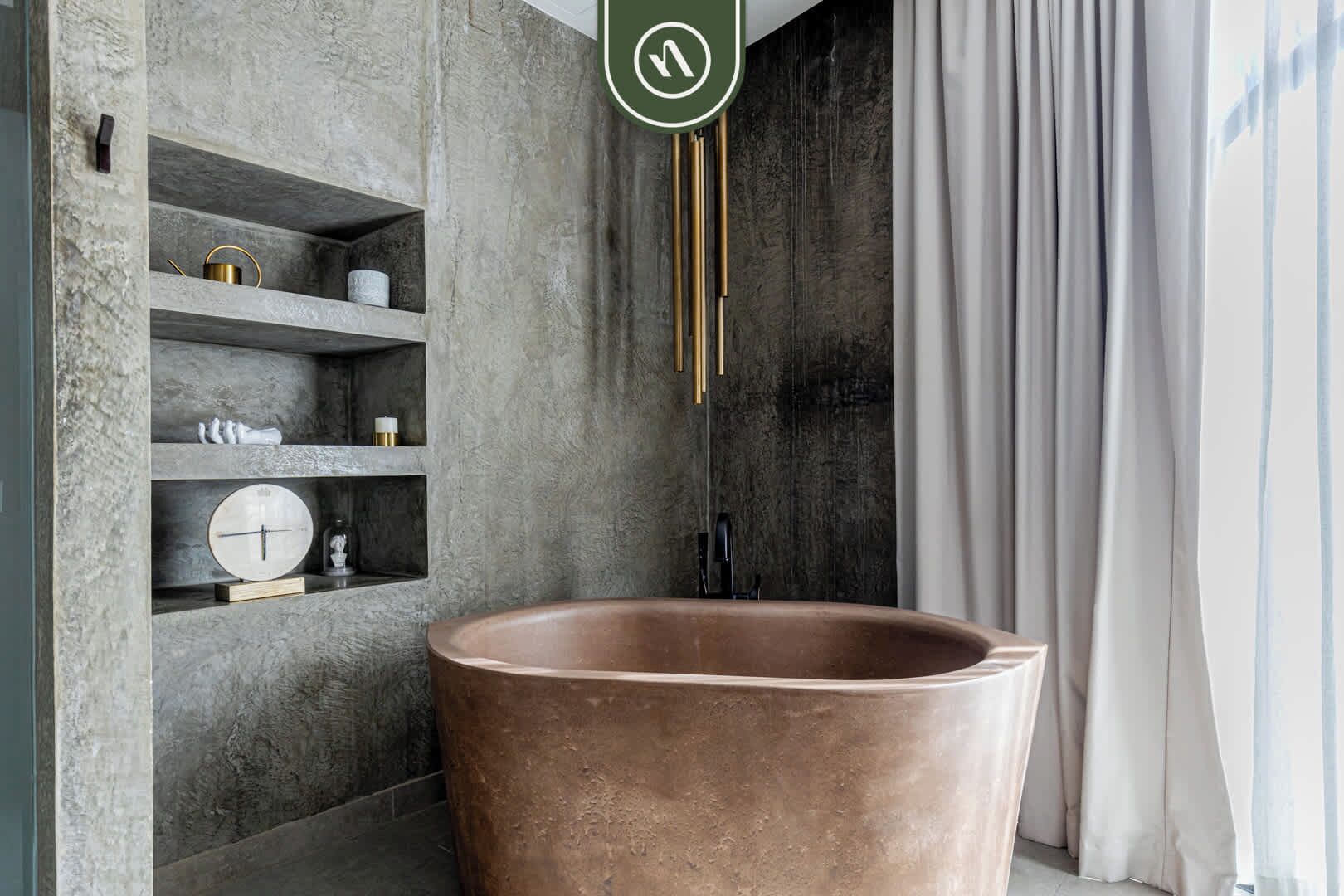 Une salle de bain avec une grande baignoire en cuivre, une horloge posée sur une étagère et un porte-serviettes.
