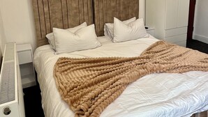 Un llit ben fet amb un llençol marró, almoines blanques i un capçal de llit.