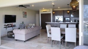 Un salon moderne comprenant un canapé, une table à manger et des chaises. Il y a également un coin cuisine avec des placards et un plan de travail.