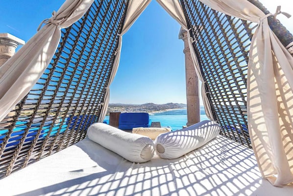 A hammock with a view of the sea and a cityscape.