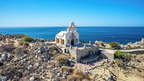 A white church with a bell tower, surrounded by rocky terrain and a view of the sea. - Two Bdrm House With Ocean View in Cabo (Cabo San Lucas)