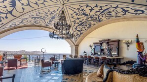 An indoor-outdoor lounge with a bar, seating, and a view of the mountains. - Two Bdrm House With Ocean View in Cabo (Cabo San Lucas)