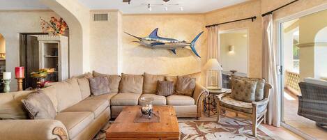A living room with a sectional sofa, a coffee table, and a decorative wall piece.