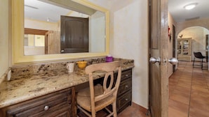 Ba ño con encimera de mármol, una silla de madera y un espejo grande.