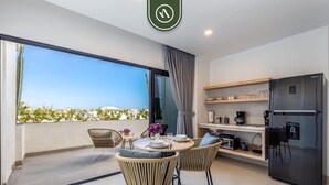 A modern apartment with a balcony, a dining area with wicker furniture, a kitchen with a black refrigerator, and a view of the city. - Amazing Studio - Terrace Overlooking the Marina (Cabo San Lucas)