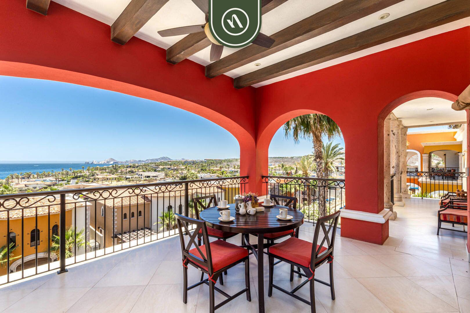 A balcony with a table and chairs, overlooking a coastal view.