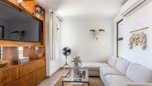 A modern living room with a wooden cabinet, a glass coffee table, a white sofa, and a mounted animal skull. - Chic 2BR House - Pedregal - Private Rooftop - Pool (Cabo San Lucas)