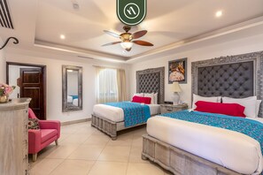 A hotel room with two beds, a ceiling fan, a mirror, a dresser, and a pink chair.