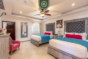 A hotel room with two beds, a ceiling fan, a large mirror, and a decorative headboard. - Great Condo With Private Balcony - Ocean View (Cabo San Lucas)