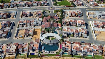 Vista aérea de um bairro residencial com uma entrada circular central, várias casas e uma piscina.