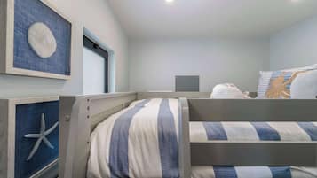 Quarto com beliches, uma ilustração emoldurada da costa e uma janela.