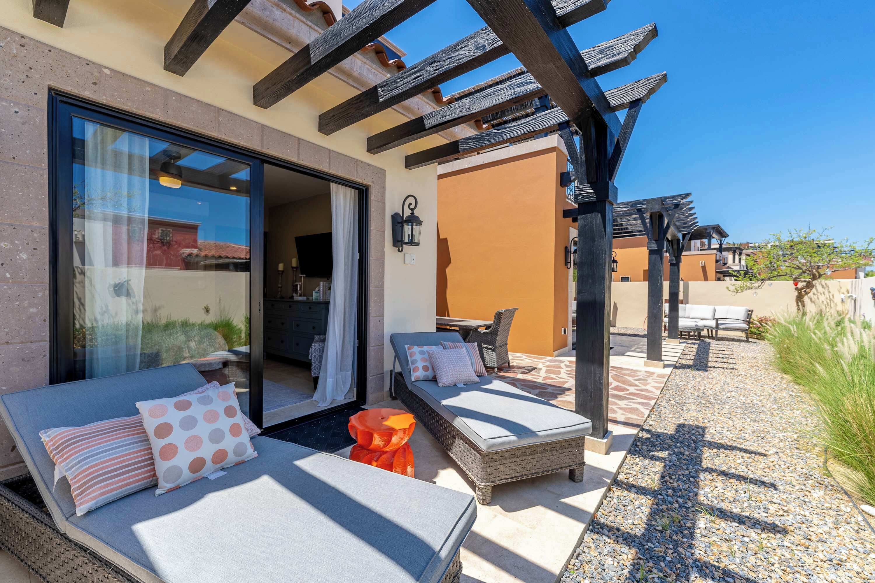 Un espace extérieur aménagé avec des fauteuils et une table, une structure en forme de pergola et une vue sur les bâtiments environnants.