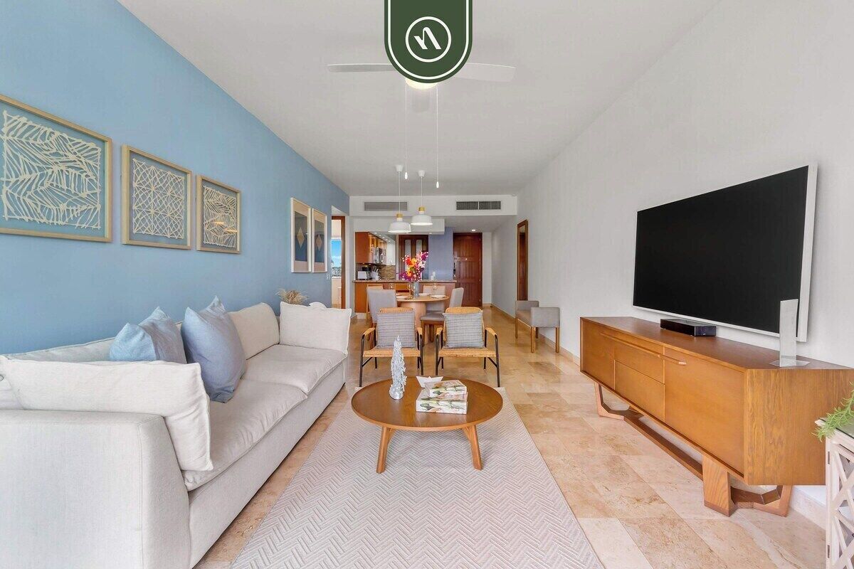 A modern living room with a sofa, coffee table, TV, and artwork on the walls.