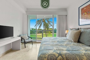 Une chambre d’hôtel équipée d’un lit, d’un bureau, d’une chaise, d’une télévision et d’un balcon donnant sur un terrain de golf.