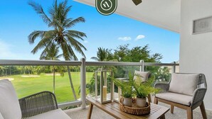 Ein Balkon mit Korbmöbeln, einem Holztisch und einem Blumentopf.