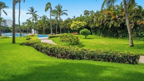 Üppige grüne Landschaft mit Swimmingpool, Palmen und gepflegtem Garten.