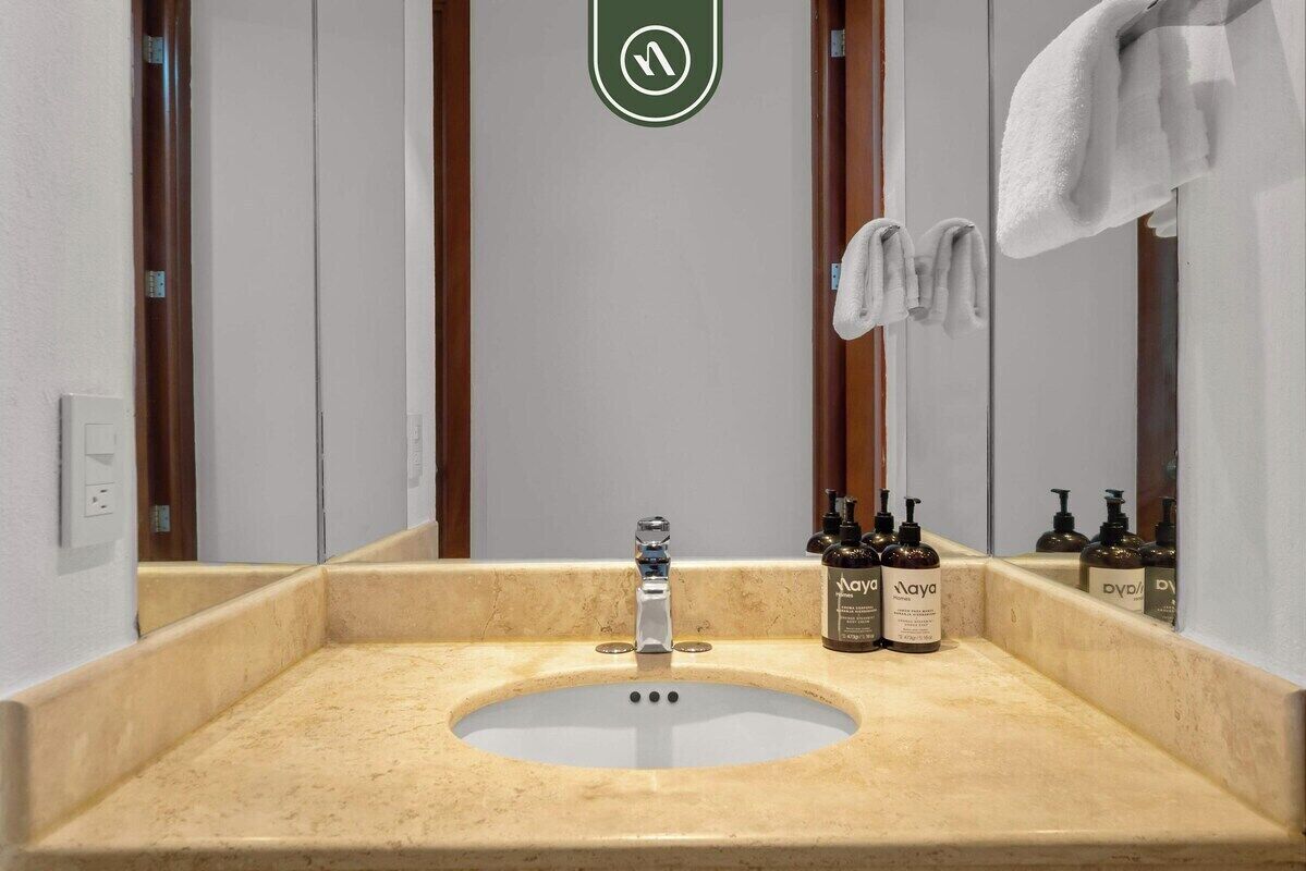 Et badeværelse med vask, spejl, håndklædestativ og toiletartikler.