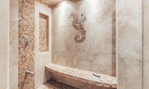 Un bagno con parete in mosaico, una panca e un motivo a cavalluccio marino.