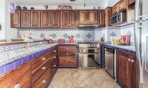 Una cucina con mobili in legno, un fornello, un forno e un microonde.