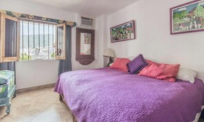 Una camera da letto con un letto, una finestra con grate, uno specchio e due quadri appesi al muro.