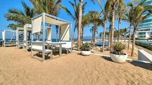 A beachside hotel with palm trees, a pool, and beach chairs. - Oceanfront 2BR Condo -private Balcony - Beach (Nuevo Nayarit)