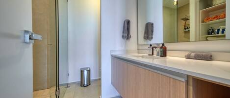 Une salle de bain moderne avec une douche à parois de verre, un meuble-lavabo blanc avec un miroir et un porte-serviettes.