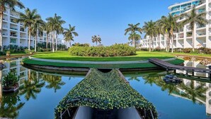 A hotel with a central water feature, palm trees, and a well-maintained lawn. - Oceanfront 2BR Condo -private Balcony - Beach (Nuevo Nayarit)