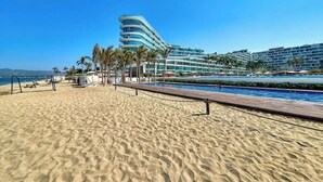 A beach resort with a pool, palm trees, and a modern hotel structure. - Oceanfront 2BR Condo -private Balcony - Beach (Nuevo Nayarit)
