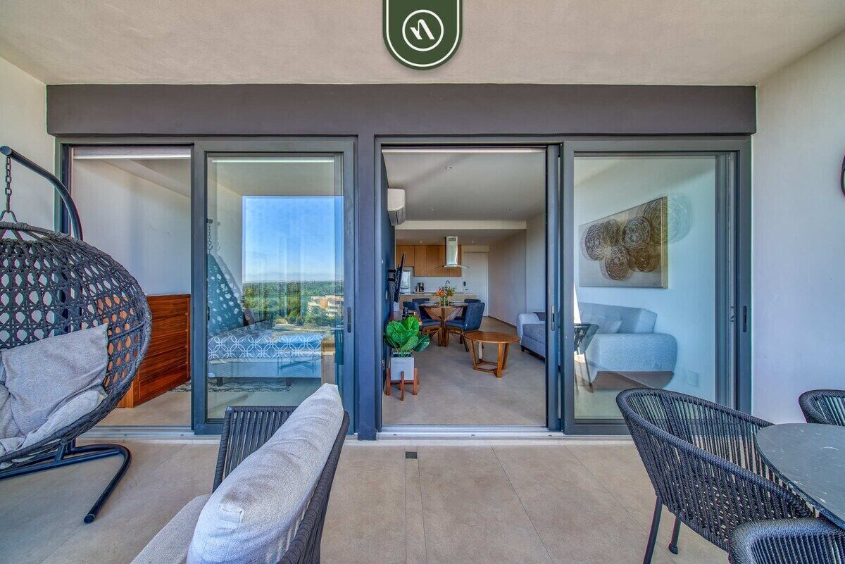 Un appartamento moderno con un balcone, un'area pranzo e un soggiorno.