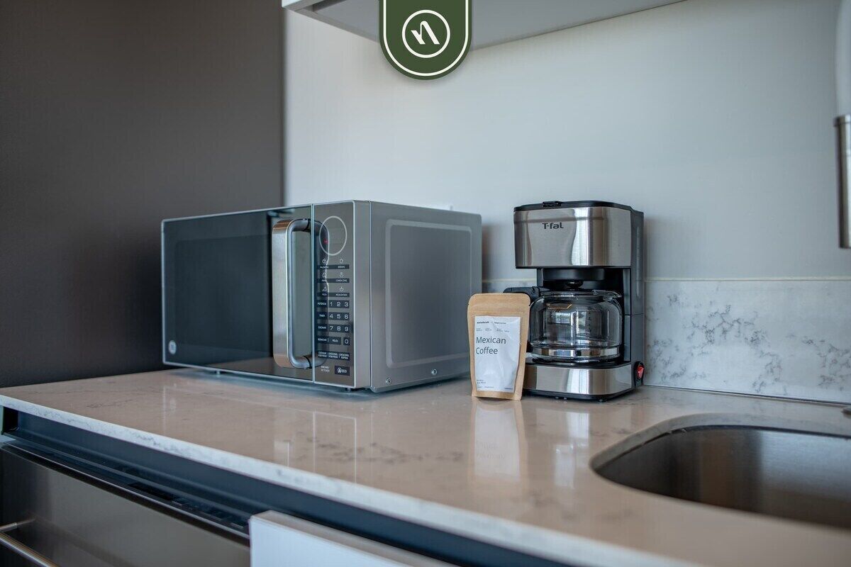 A kitchen with a microwave, coffee maker, and a coffee pod on the counter.