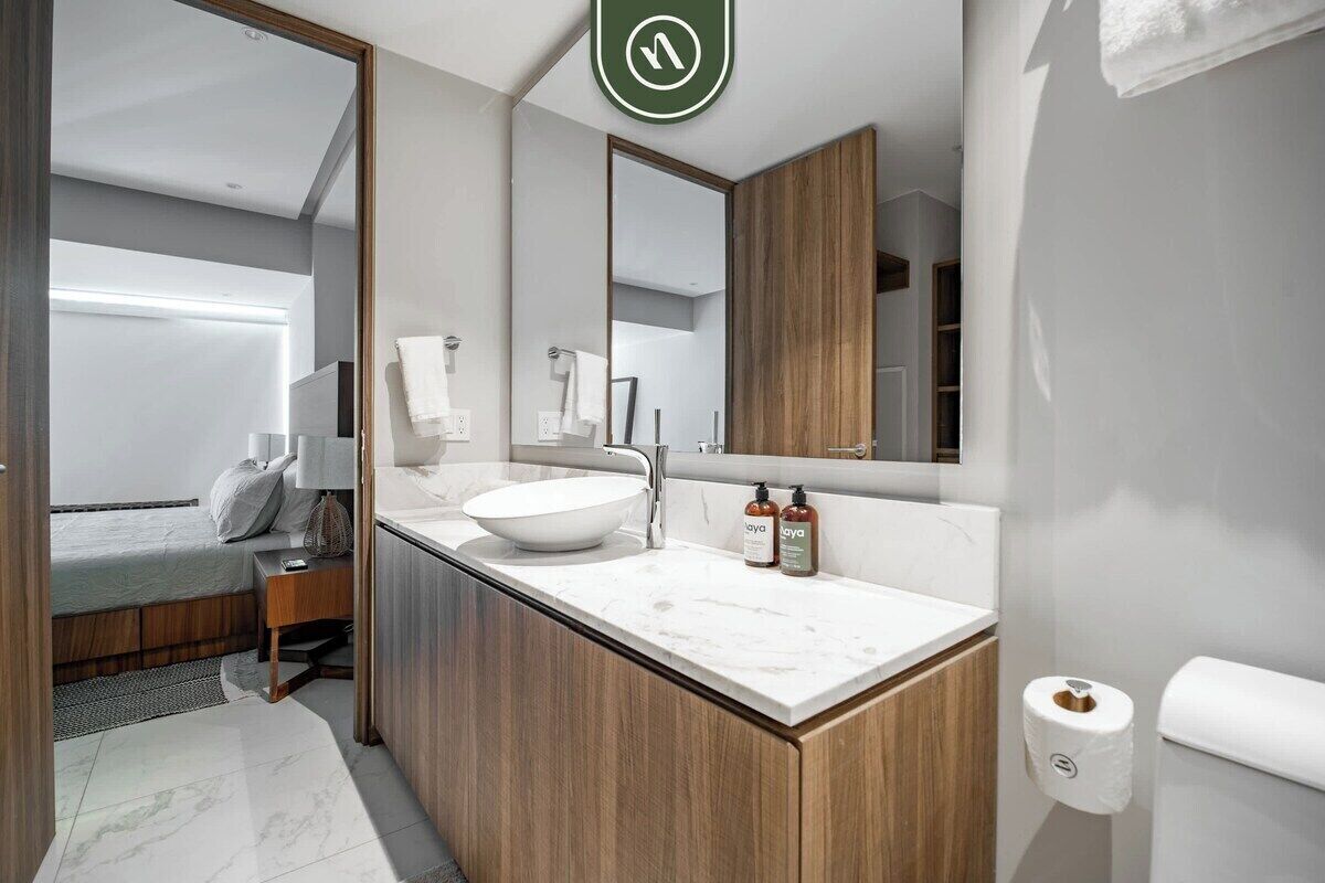 Een moderne badkamer met een grote spiegel, een wastafel en een toilet.