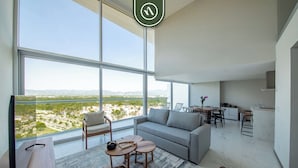 A modern living room with a large window, a sofa, a dining area, and a kitchen. - Stunning Oceanview Two Story Condo - Beach - Gym (Nuevo Nayarit)