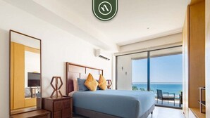 A bedroom with a bed, a dresser, a mirror, and a view of the ocean. - Oceanview 1 BR Condo - Private Beach - Pools (Nuevo Nayarit)