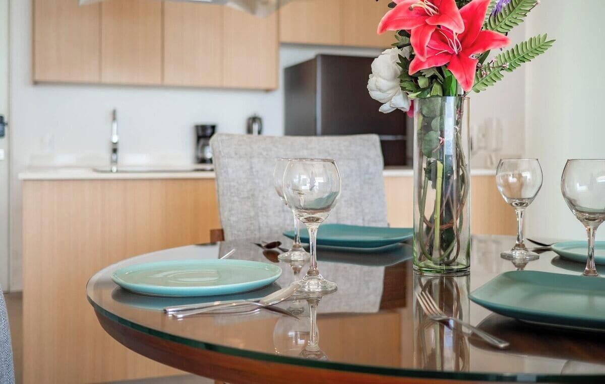 A dining table with a vase of flowers, a glass of water, and a plate.