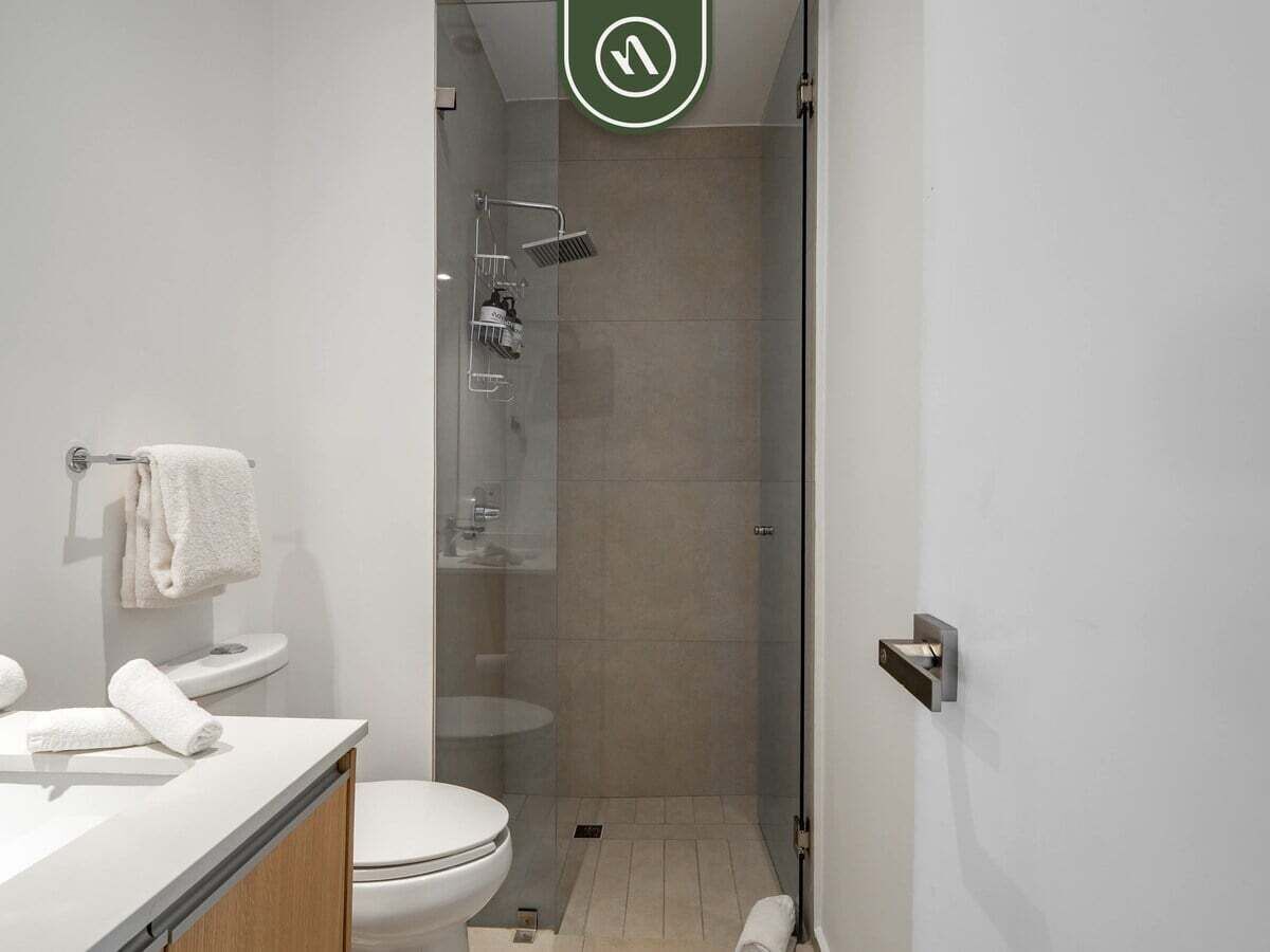 Un baño moderno con inodoro, lavamanos y ducha.